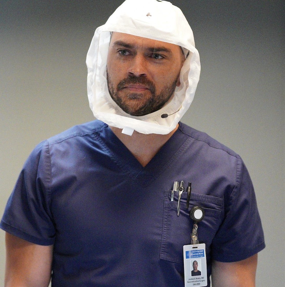 Jesse in hospital scrubs, name tag, and hazmat head covering