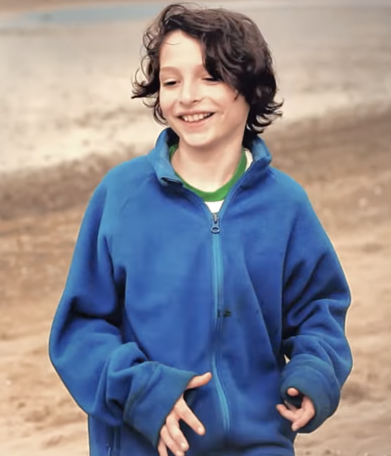 A young Finn Wolfhard smiling on the beach