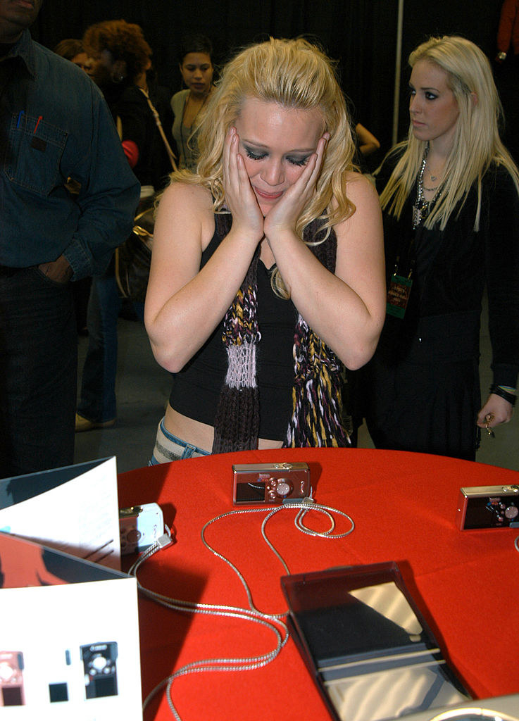 Hilary with her hands on her cheeks as she looks at a camera on a table