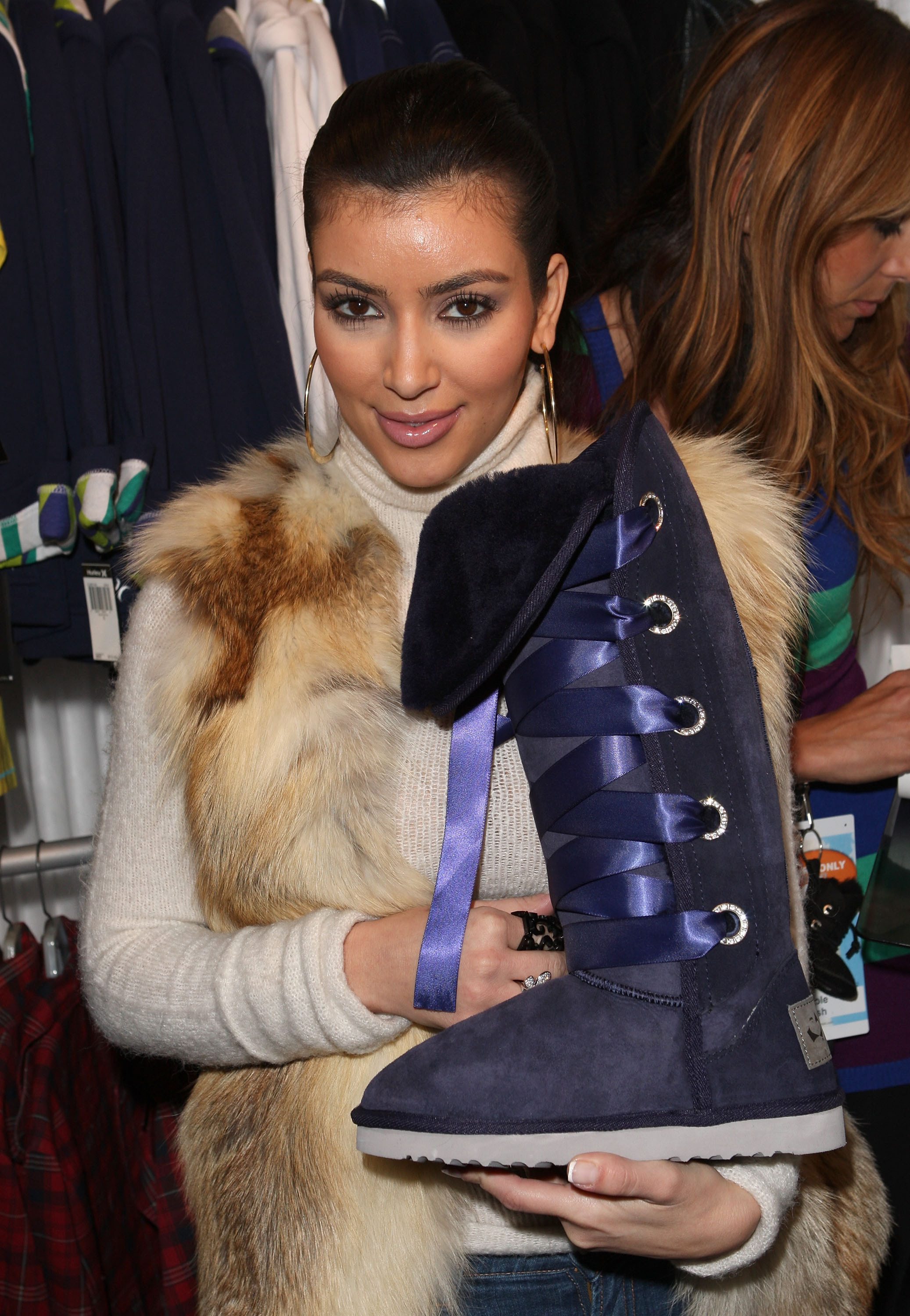 Kim holding an Ugg-type boot with ribbon laces
