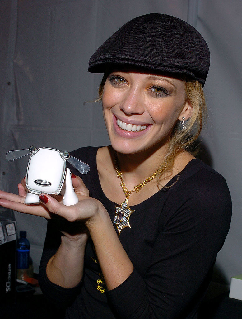 Hilary in a cap holding a robotic dog and smiling