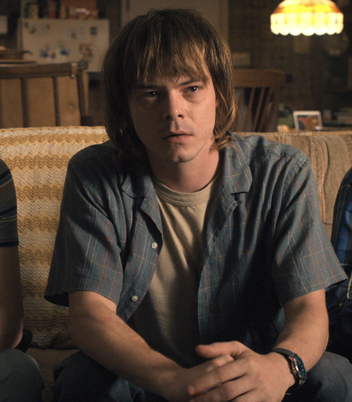 Charlie Heaton sits on a couch in &quot;Stranger Things&quot;