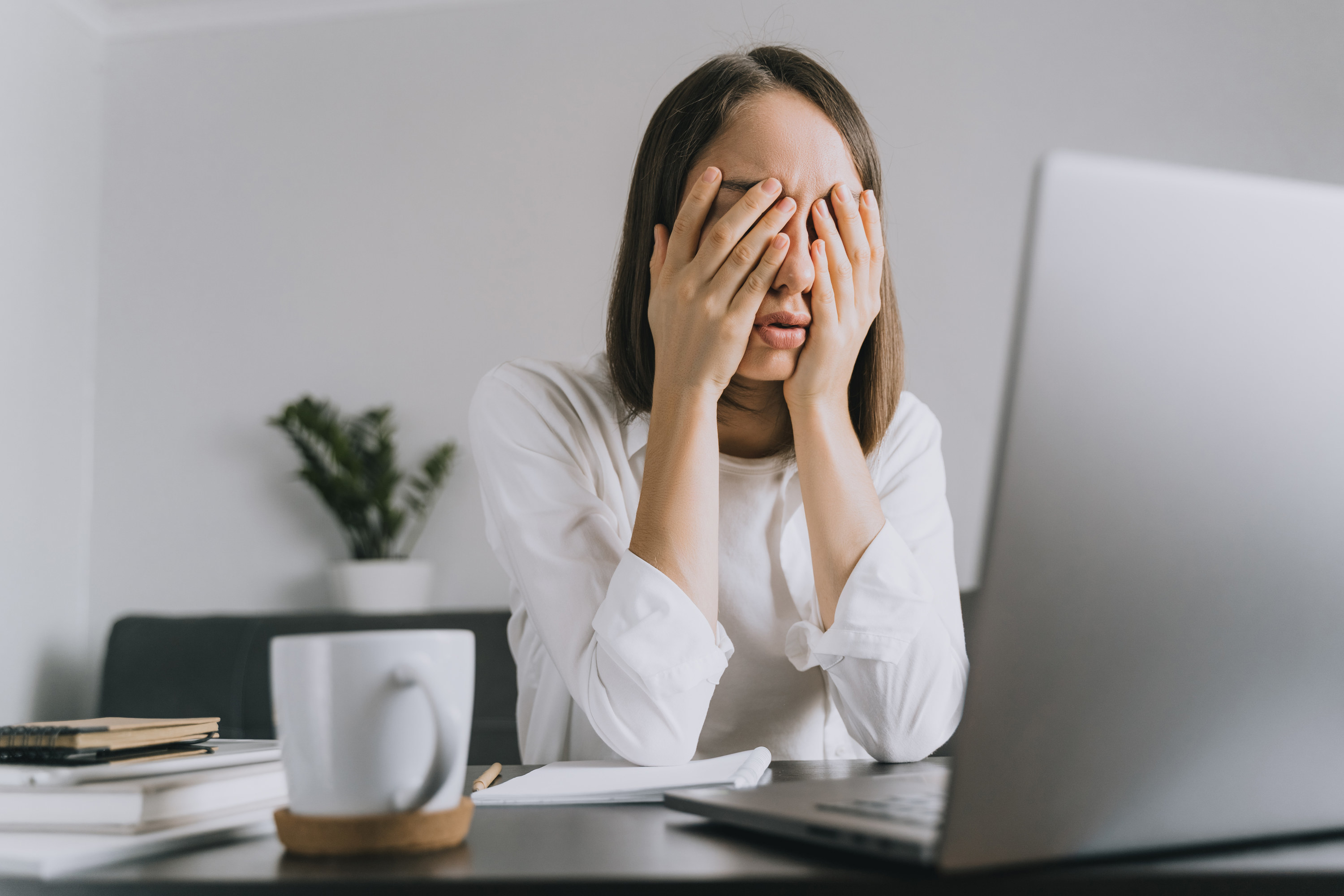 A woman covering her eyes at her desk