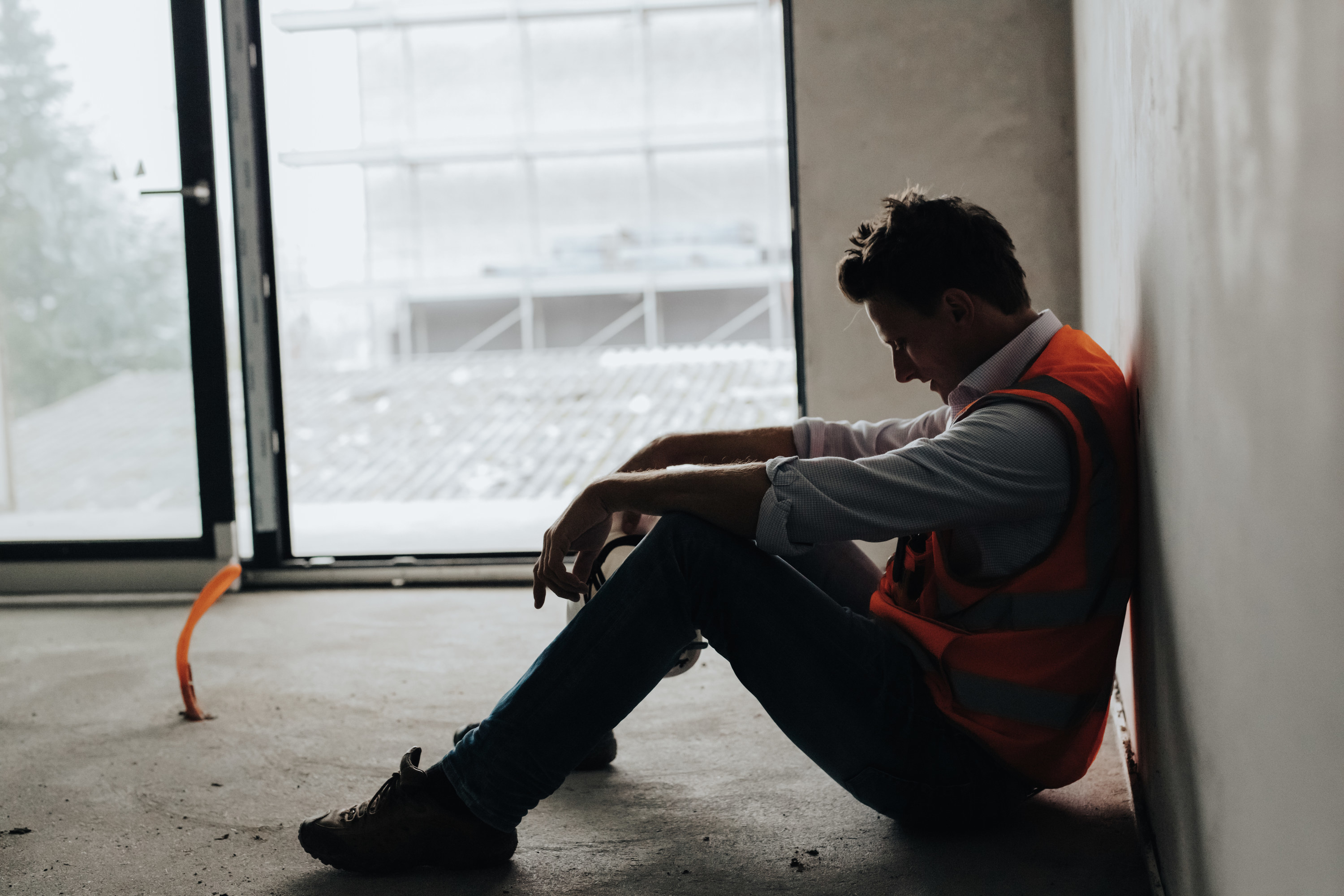 A man sitting on the floor at work and looking depressed