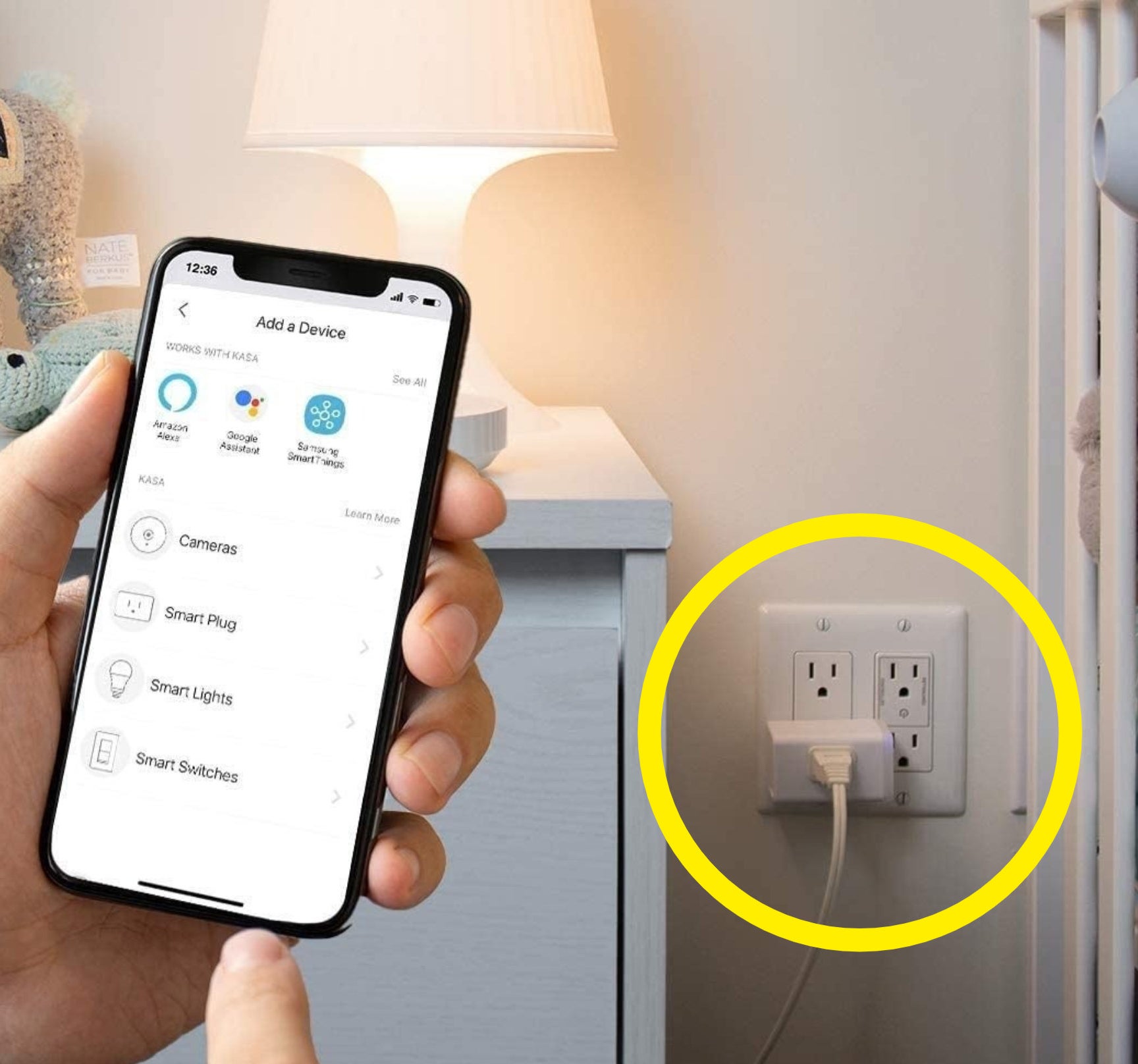 a person holding a phone in front of the smart plug beside a lamp