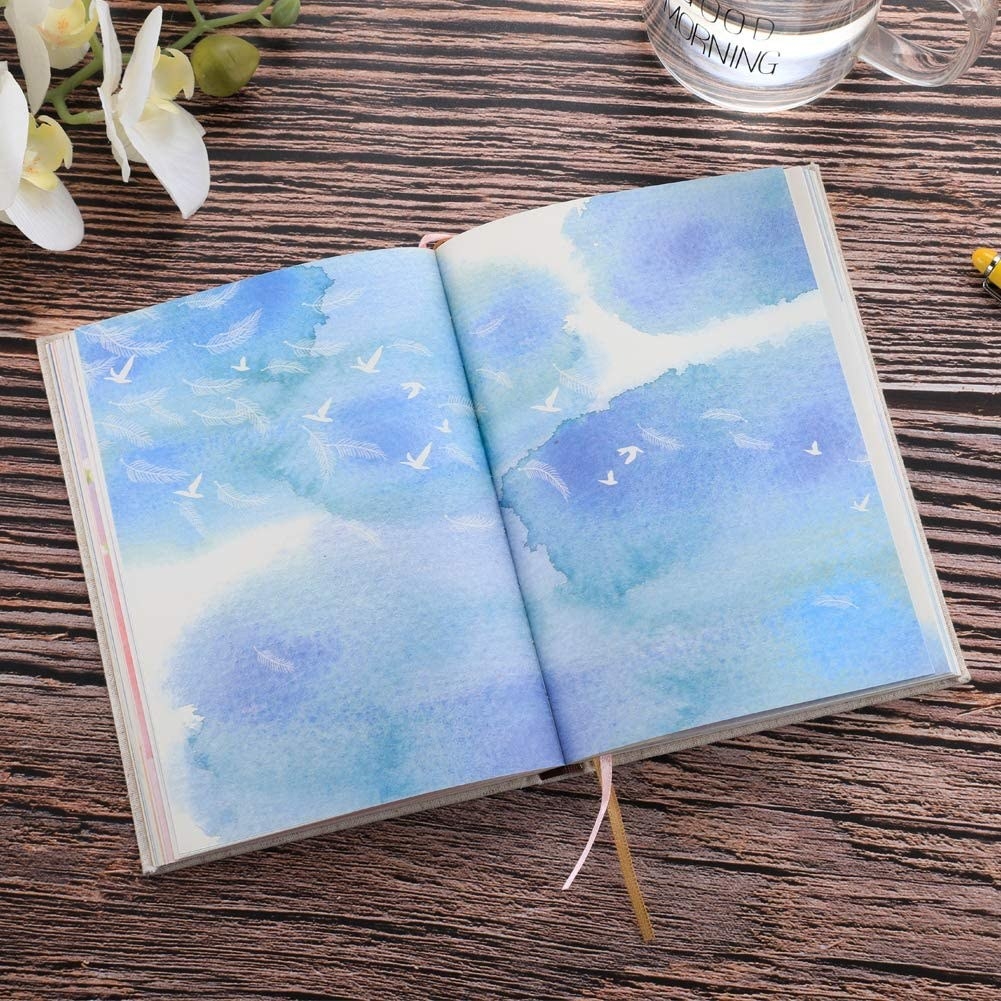 A gorgeous journal with colourful pages open on a wood surface