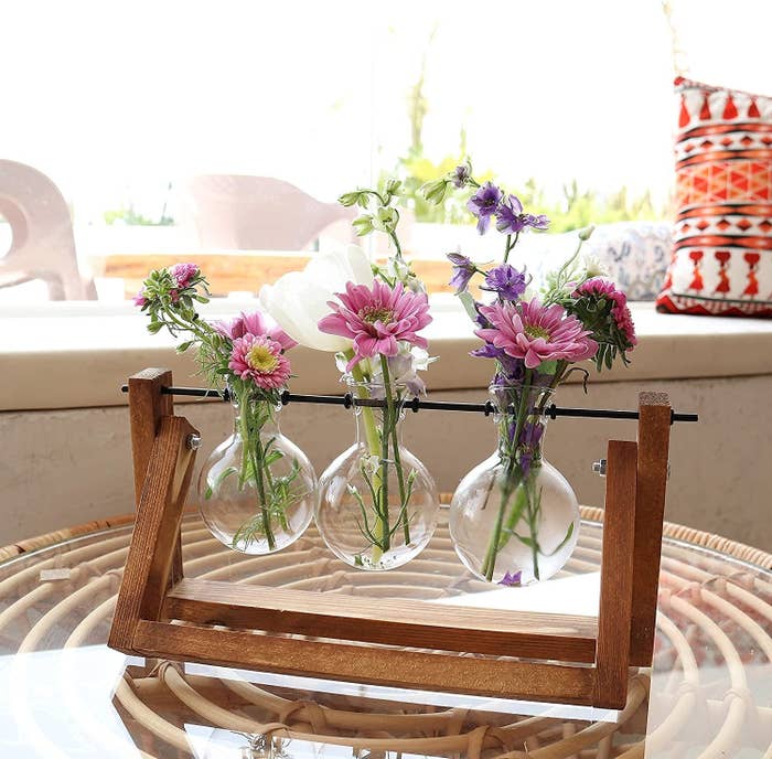 a mini bouquets of flowers in each of the three vases sitting on the stand
