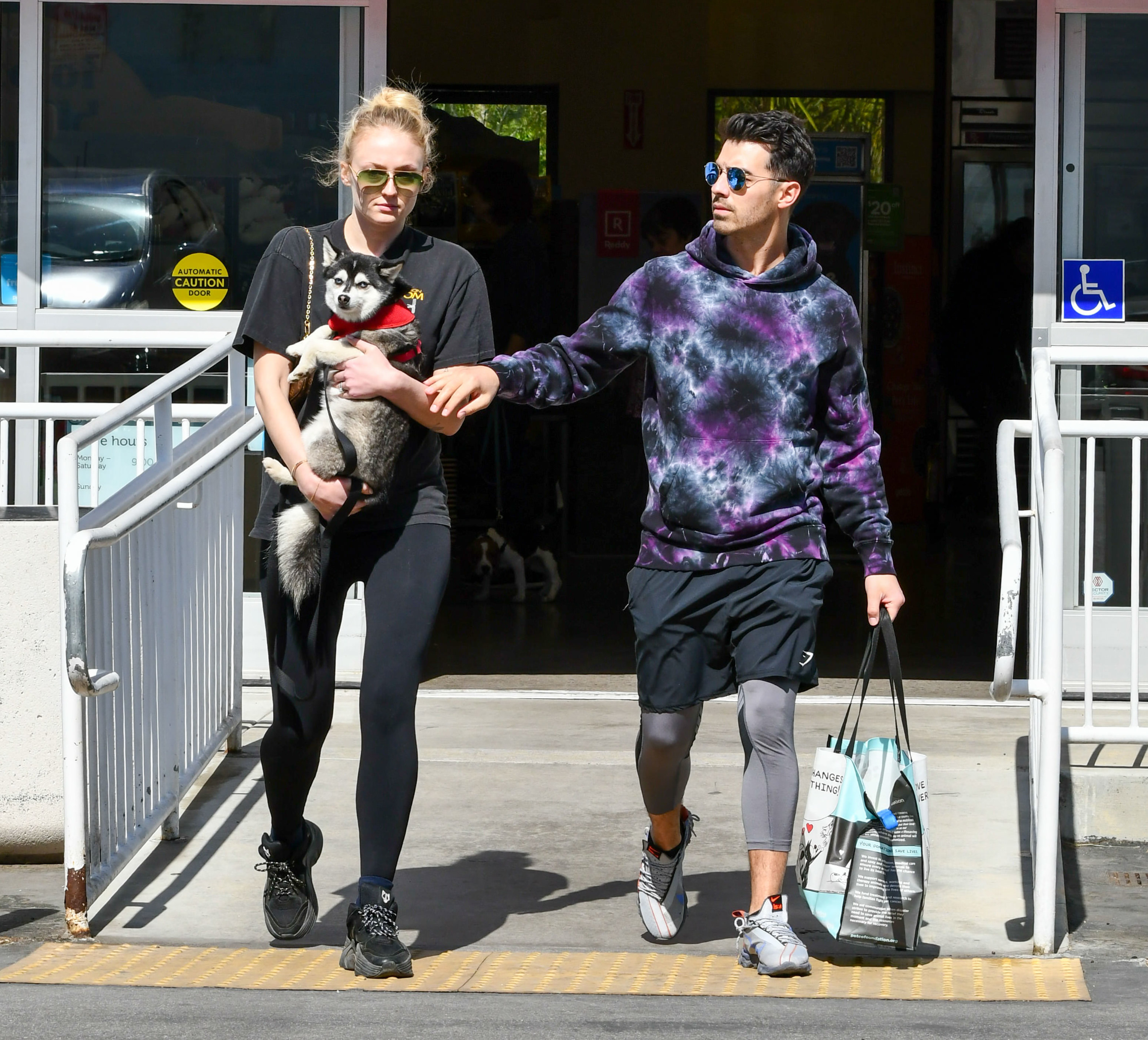 Sophie holds a dog while walking next to Joe as he carries a bag