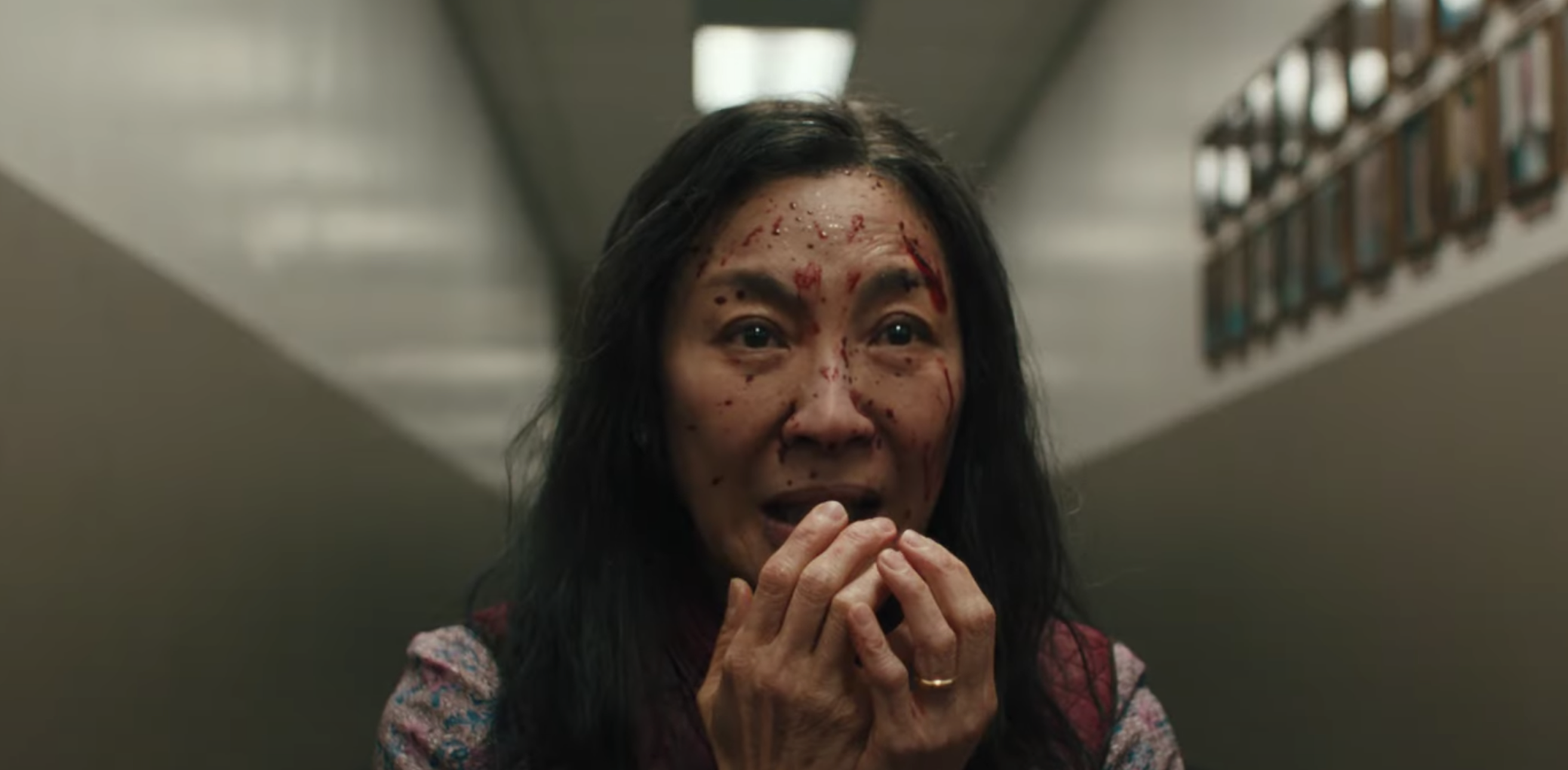 Michelle Yeoh as Evelyn with her hands over her mouth and blood on her face