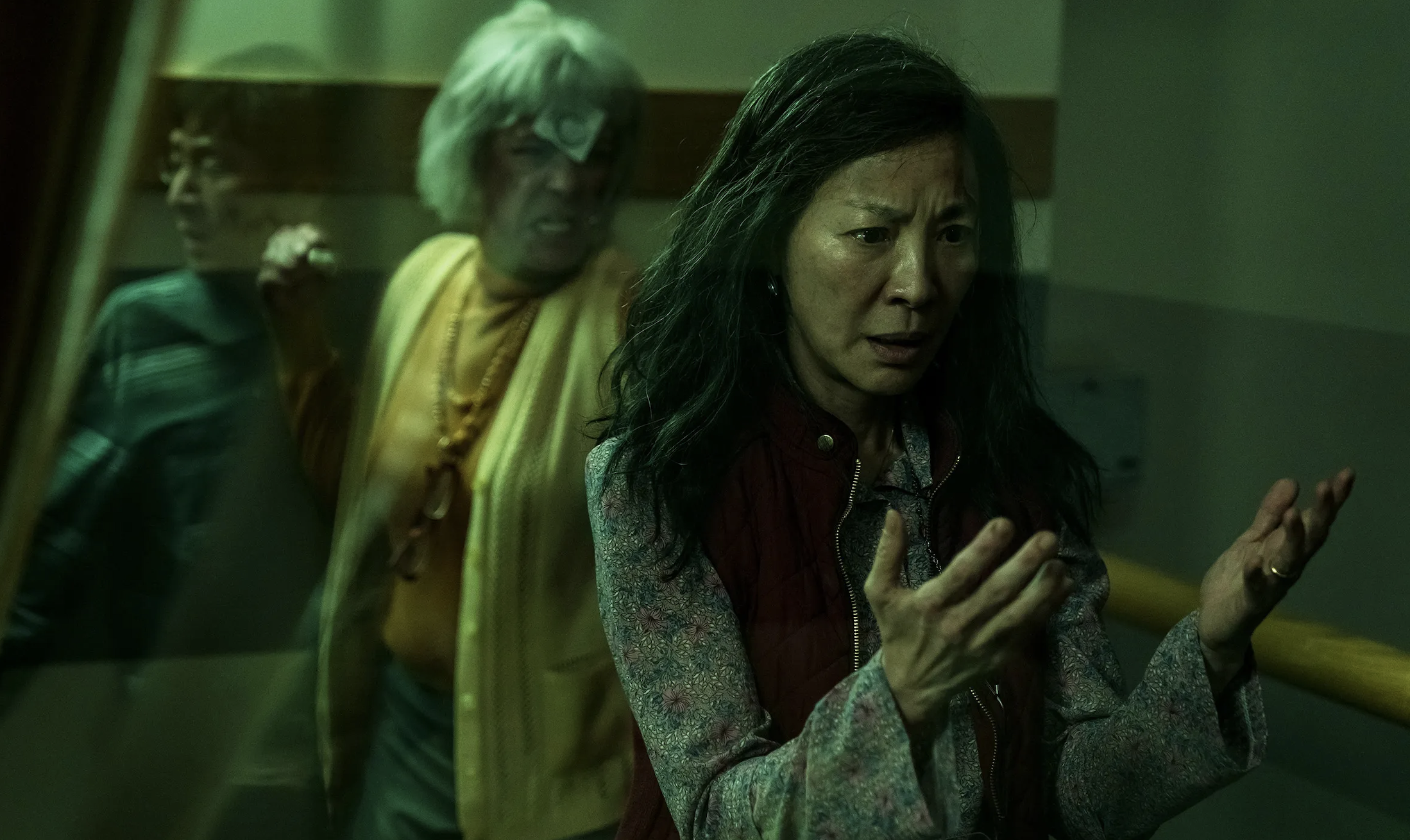 Michelle Yeoh as Evelyn with Jamie Lee Curtis as Deirdre running with a fist clenched behind her