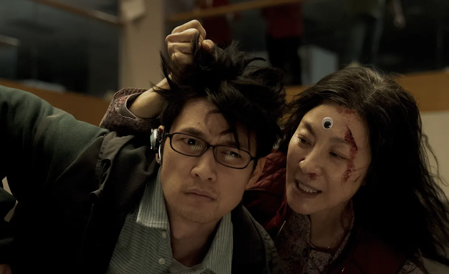 Michelle Yeoh as Evelyn holding the hair of Harry Shum Jr. as Chad