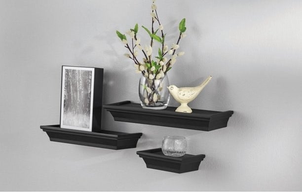 An image of a set of three black floating shelves mounted onto a wall