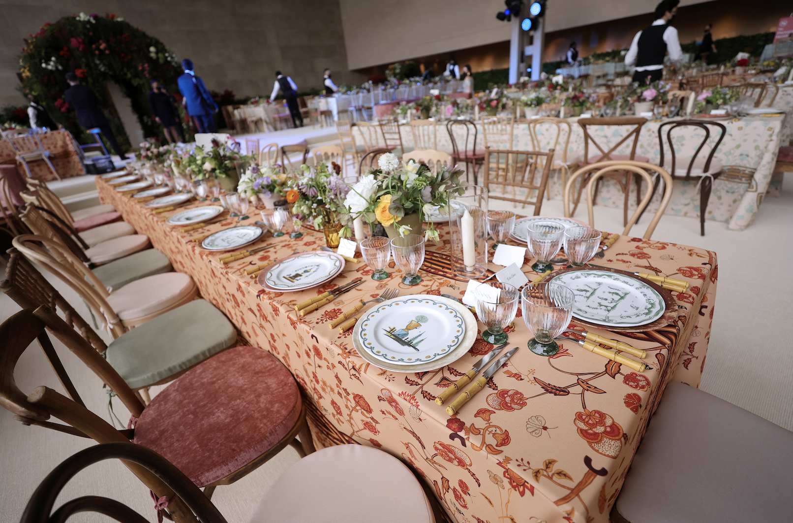 Chairs of various types and colors set at tables with fancy floral tablecloths