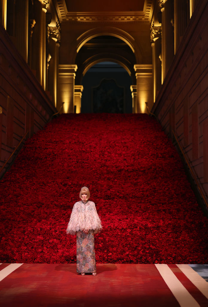Anna standing in front of backdrop that makes it look like there&#x27;s a sea of red roses behind her