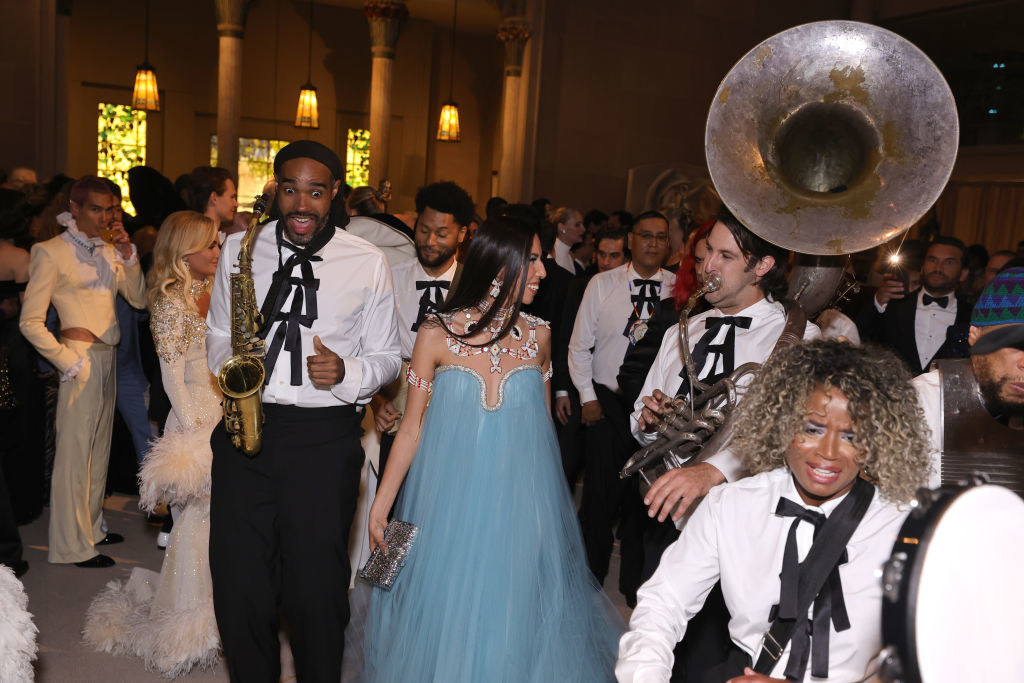 Quannah smiling as musicians play the saxophone and tuba around her