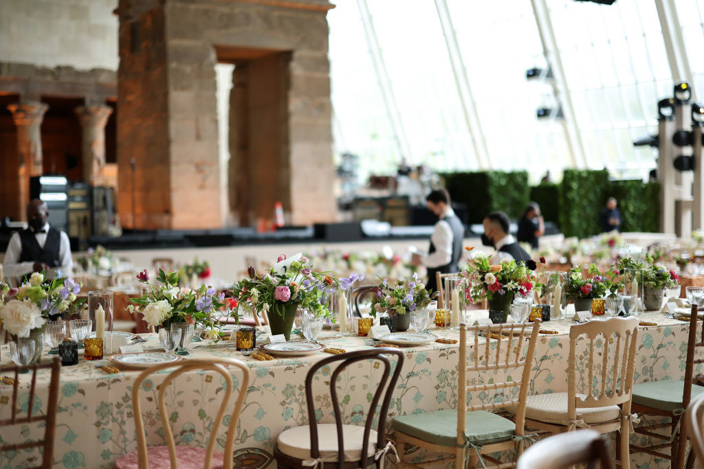 Several long tables decorated with flowers and mismatched chairs