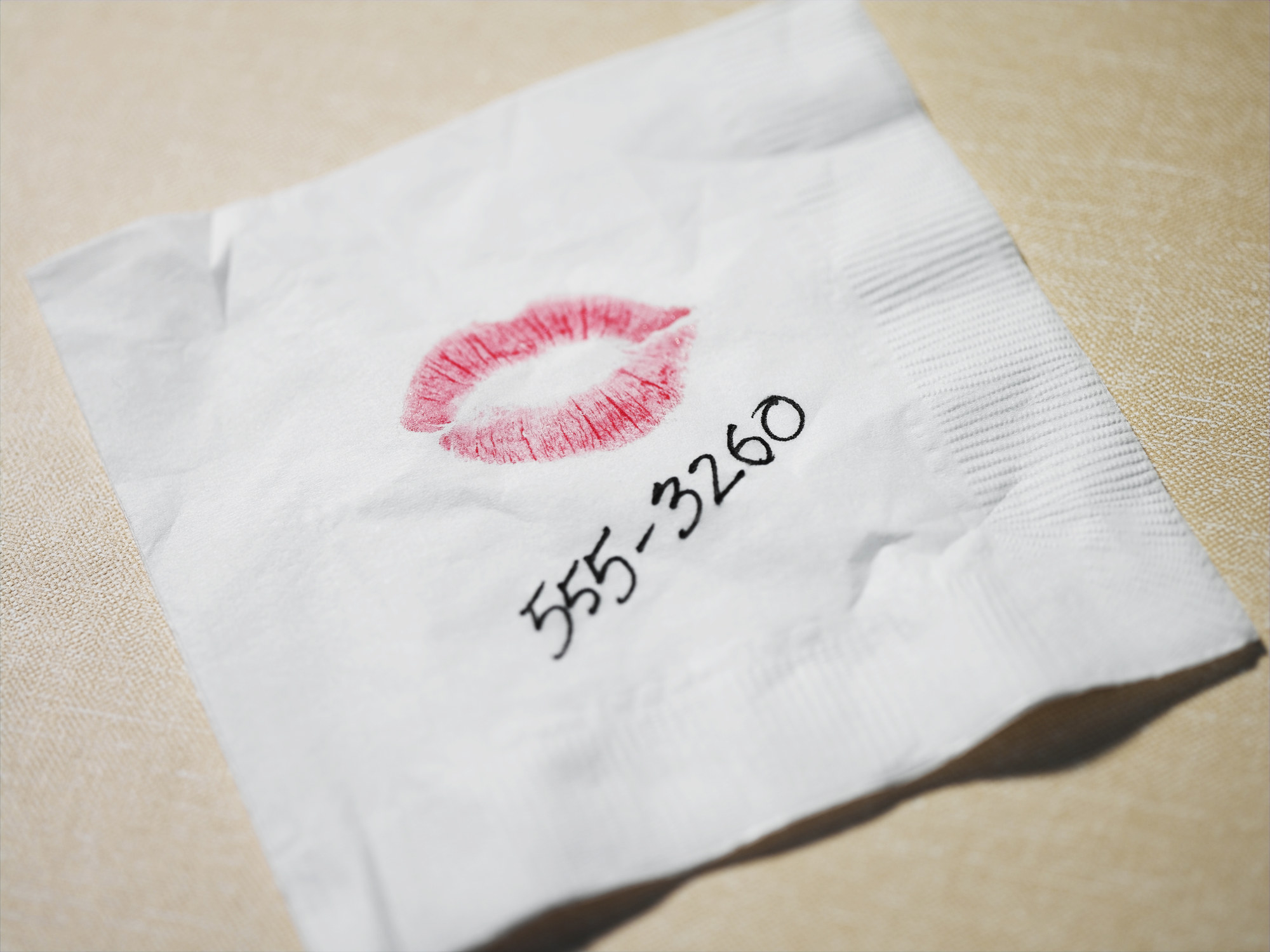 The number 555-3260 on a napkin along with the outline of lips with lipstick