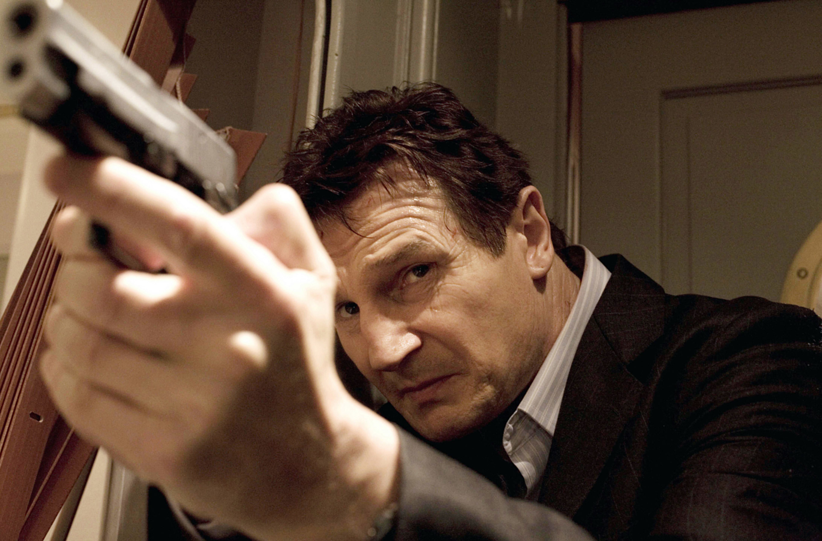 Liam Neeson aims a gun