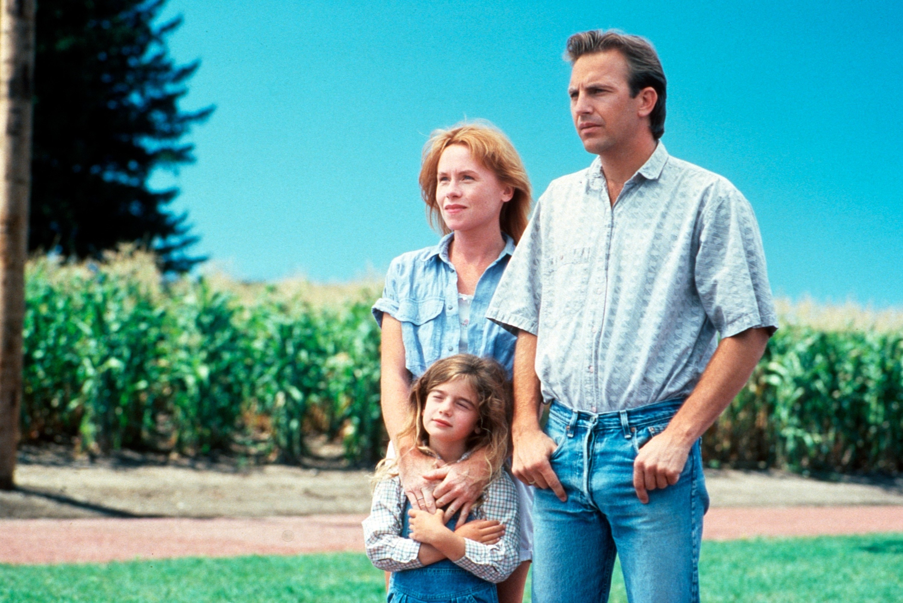 Kevin Costner, Gaby Hoffman, and Amy Madigan stand by a cornfield