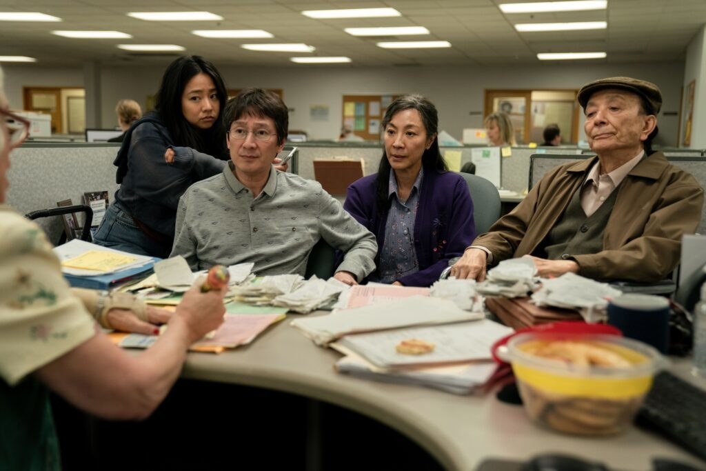 Evelyn, Joy, Waymond, and Evelyn&#x27;s father Gong Gong played by James Hong sit behind the auditor&#x27;s desk