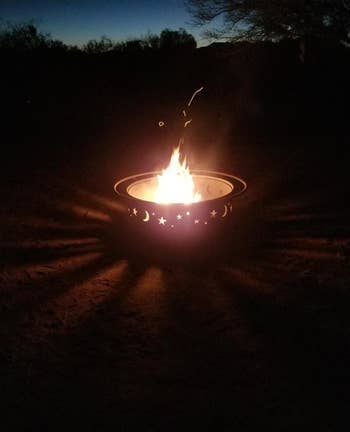a fire pit at night showing the lit up moon and stars design