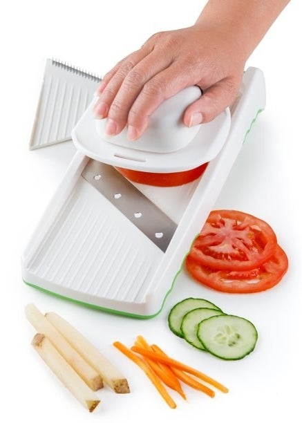 a person slicing cucumber, potatoes, and carrots with a mandolin