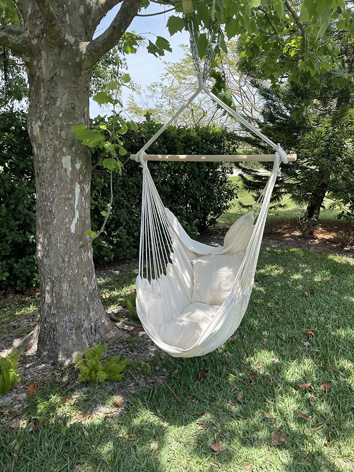 a white hanging chair hung from a tree