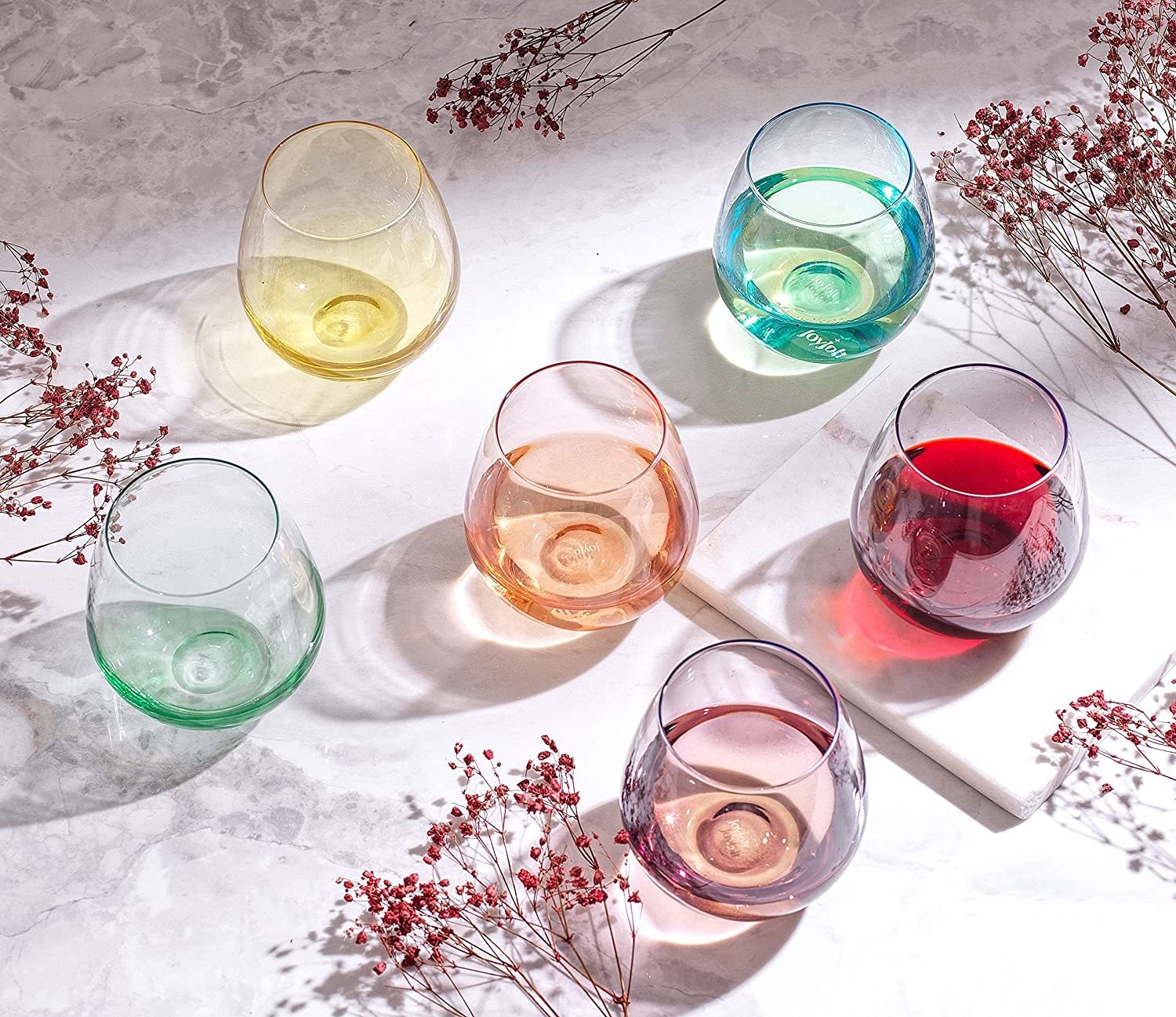 a set of colourful stemless wine glasses on a tablecloth