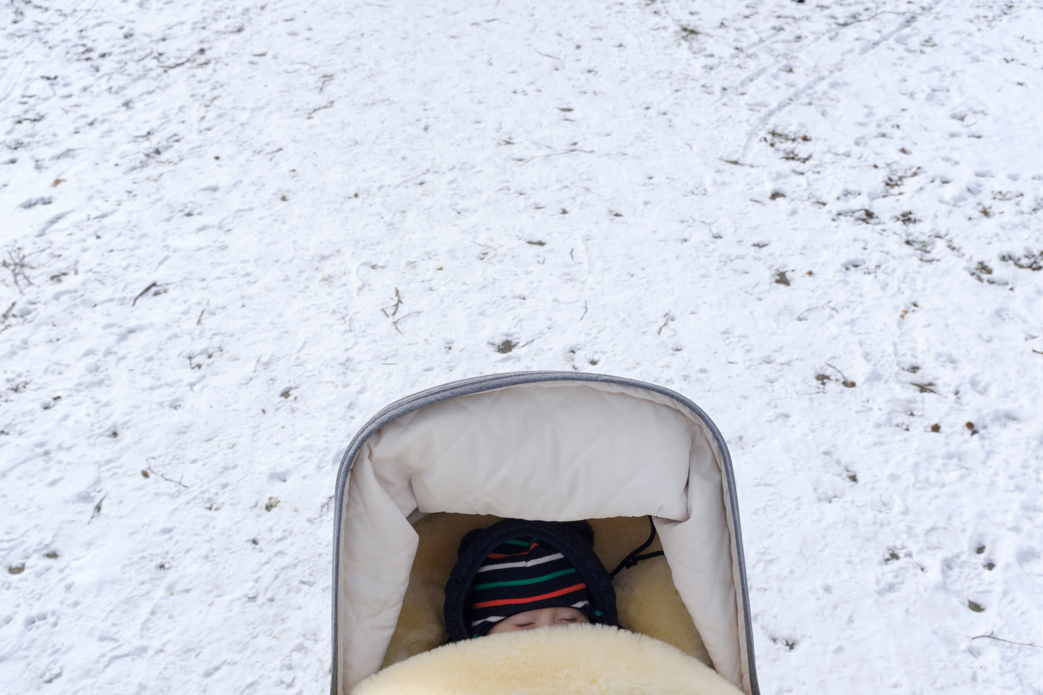 A baby sleeping in a stroller during winter