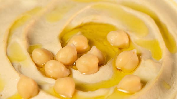 A closeup of a plate of hummus topped with chickpeas and oil