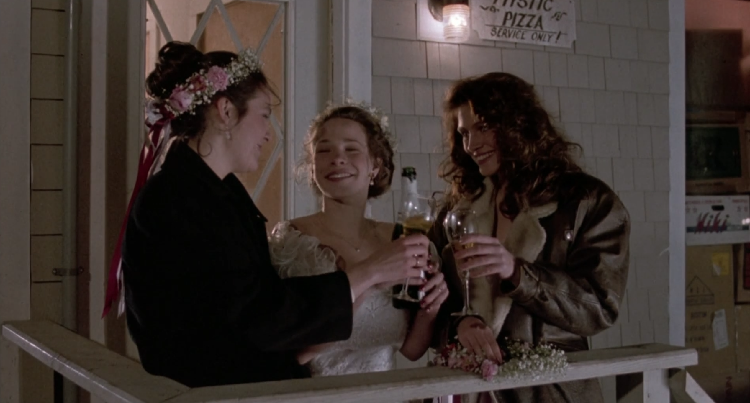 Three best friends cheering their wine glasses together at a wedding