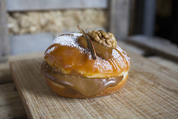 A large round donut that has caramel oozing out of the midde and dolloped on top