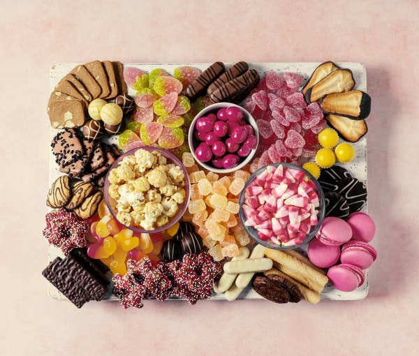 A plate that's packed with candy, popcorn, chocolate, biscuits, and macarons