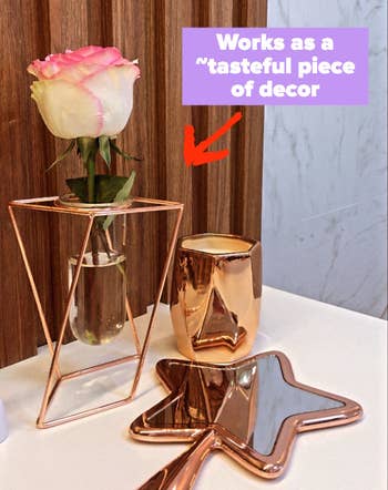 Reviewer image of rose gold and glass vase with rose inside on top of white table with rose gold decor