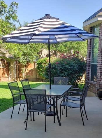 patio with square glass table and a striped umbrella on it