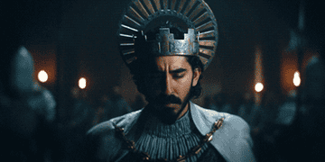 a bearded man with a large circular crown looks up