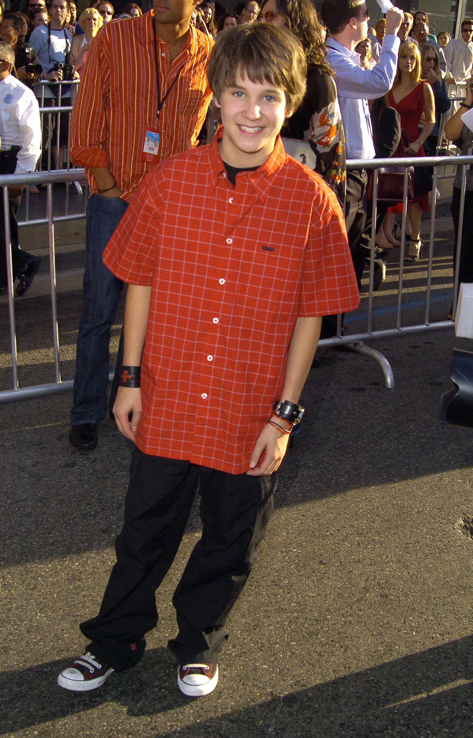 Smiling Devon in a checkered, short-sleeved shirt, loose pants, and sneakers