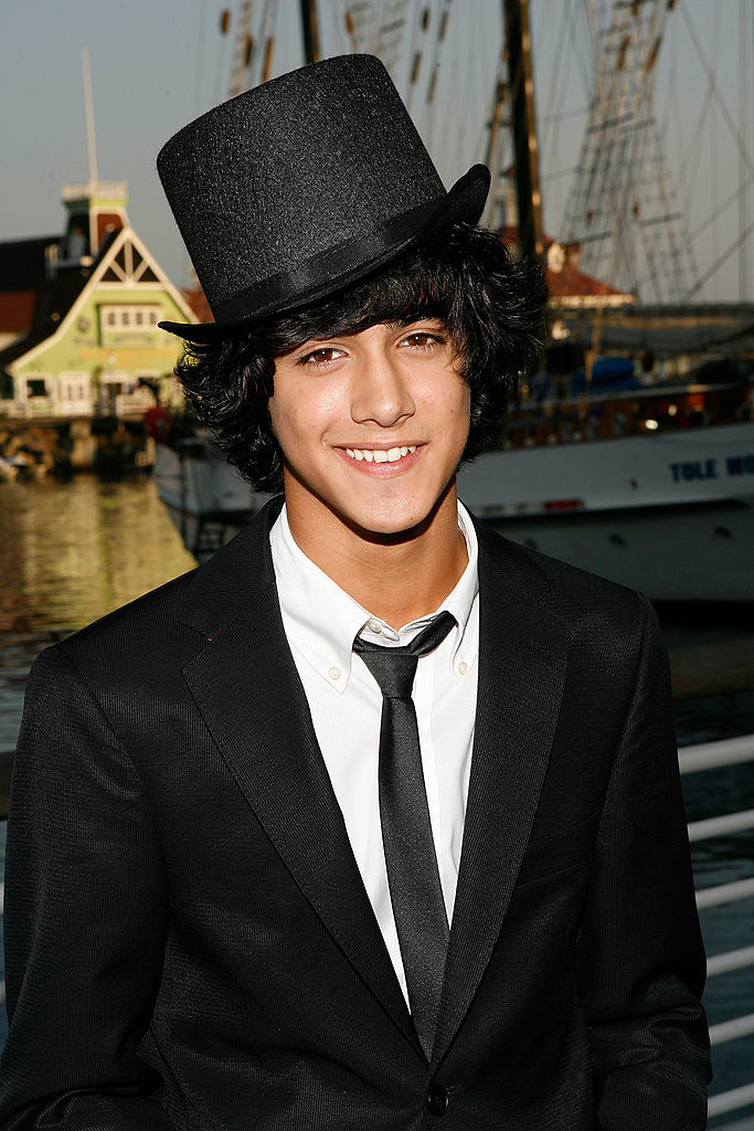 Smiling Avan in a top hat and suit and tie