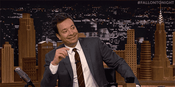 Jimmy Fallon covering his mouth with his hand and giggling