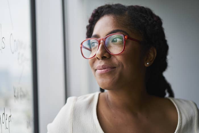 A person wearing glasses and looking out of a window