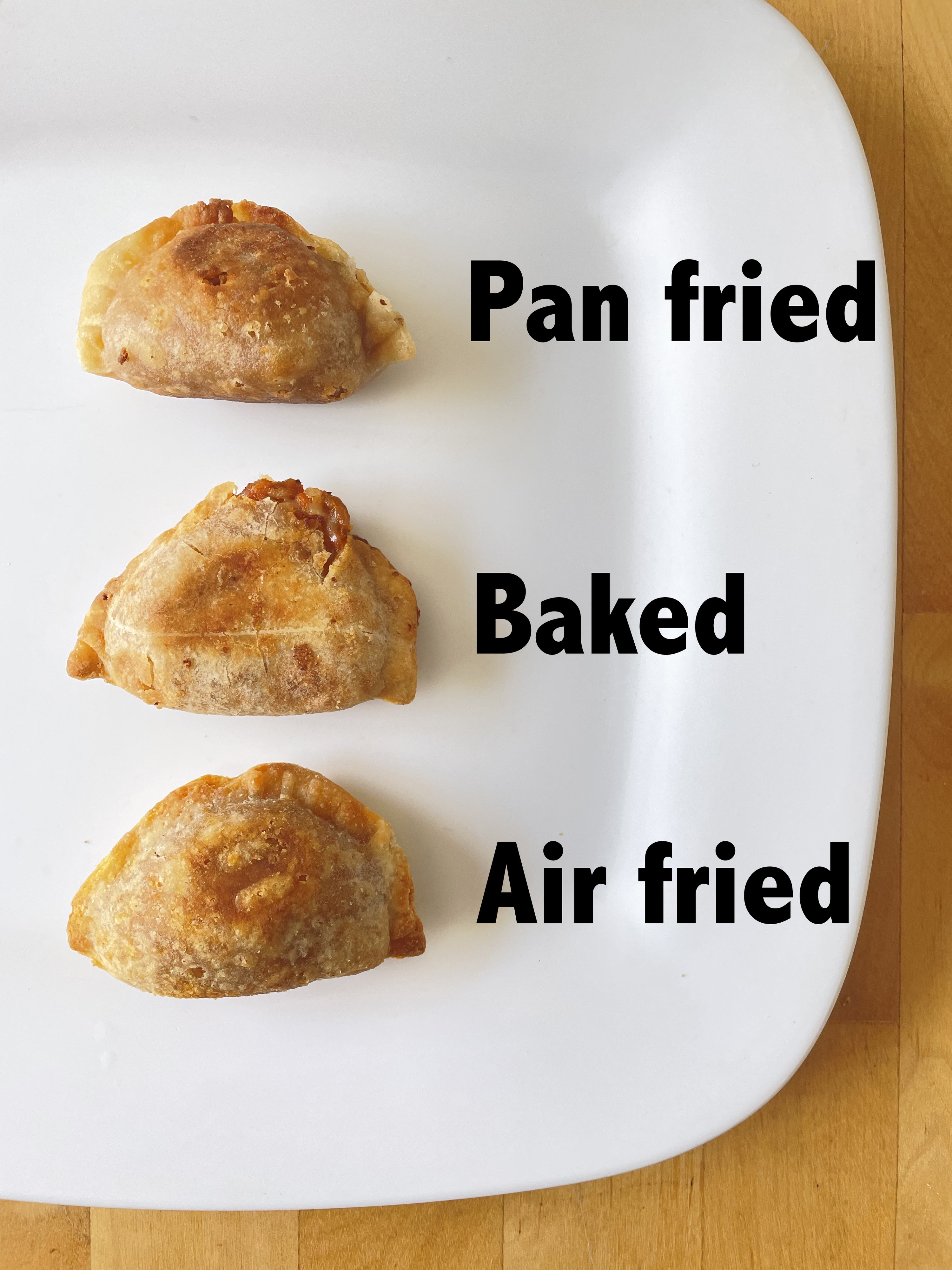 Three empanadas on a plate with the words &quot;pan-fried,&quot; &quot;baked,&quot; and &quot;air fried&quot; next to them