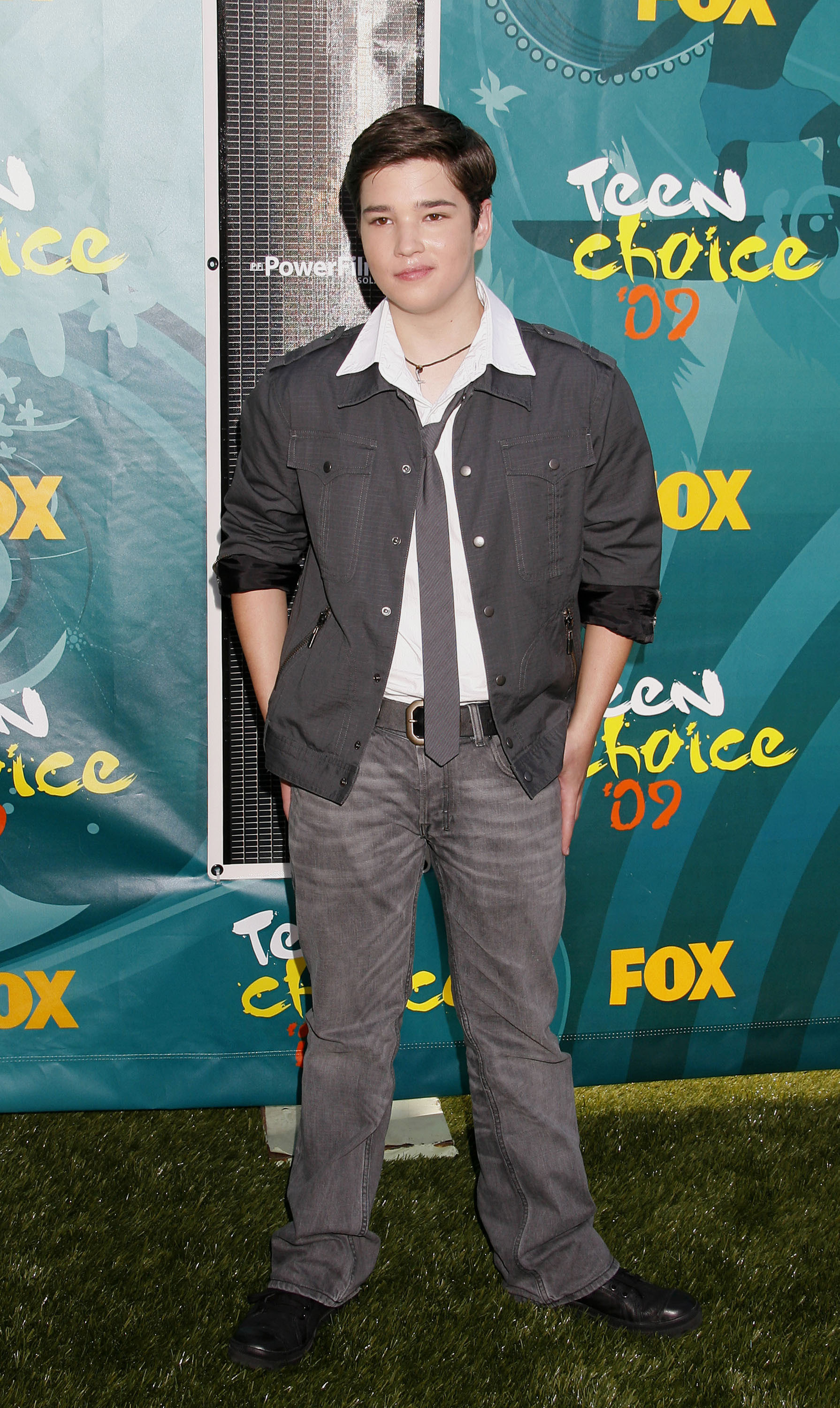 Nathan in jeans and a shirt, tie, and open jacket