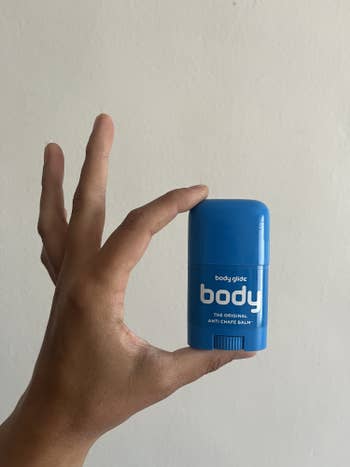 hand holding the small blue tube of anti-chafling balm