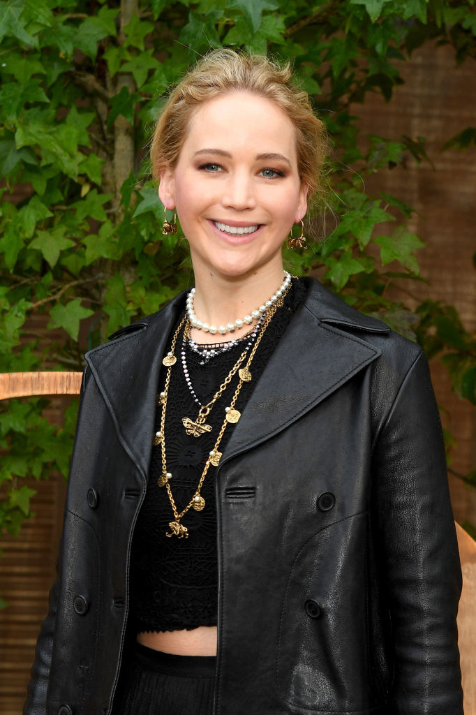 Smiling Jennifer wearing a leather jacket, midriff-baring top, and many necklaces