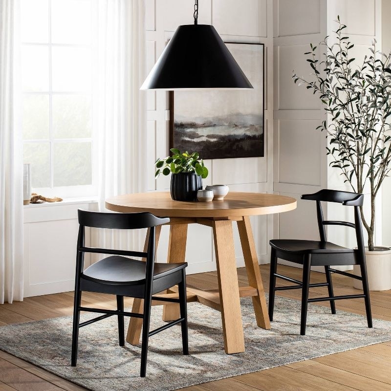 The black matte pendant light hangs above a table and chairs