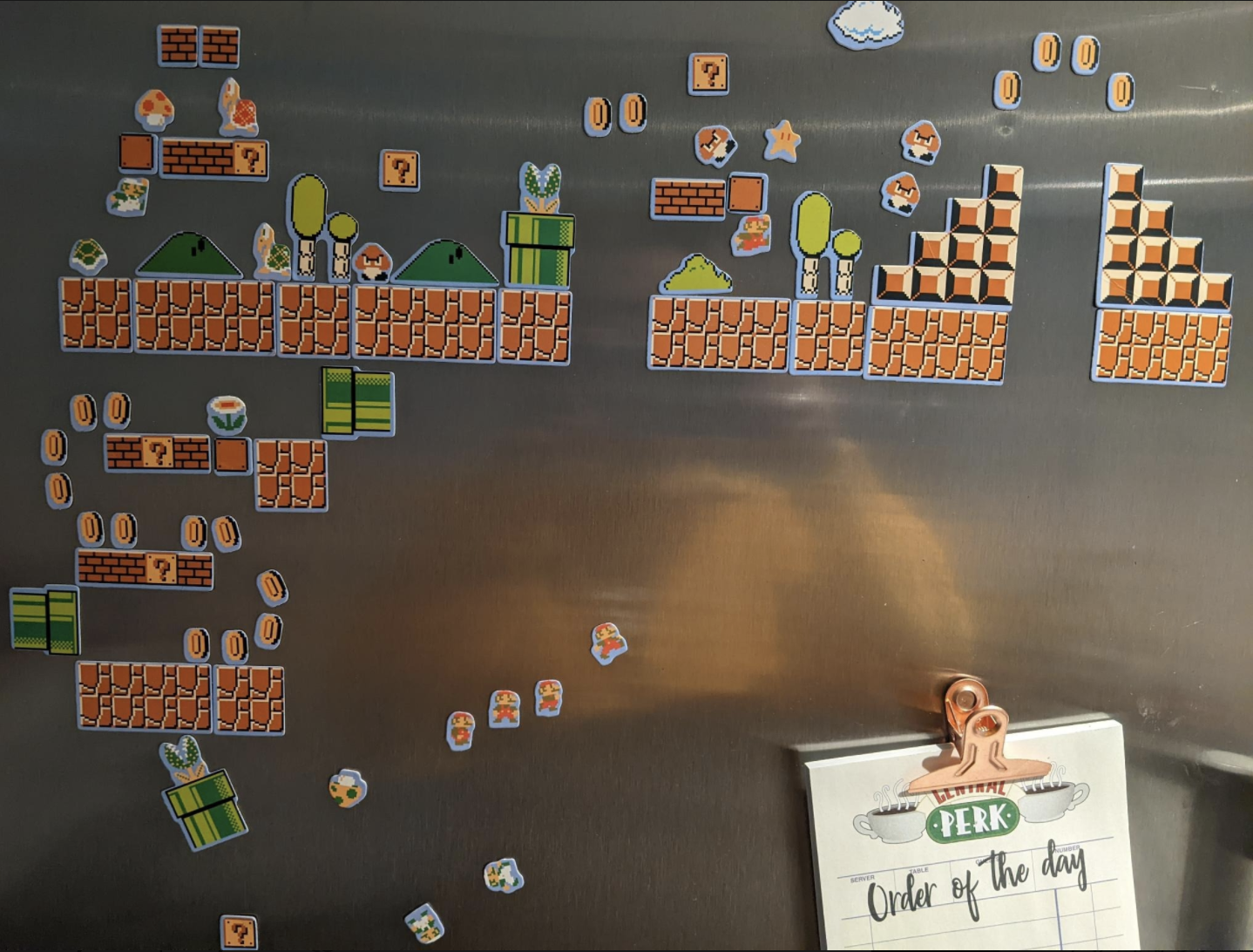 Super Mario Bros. magnets arranged on a stainless steel fridge