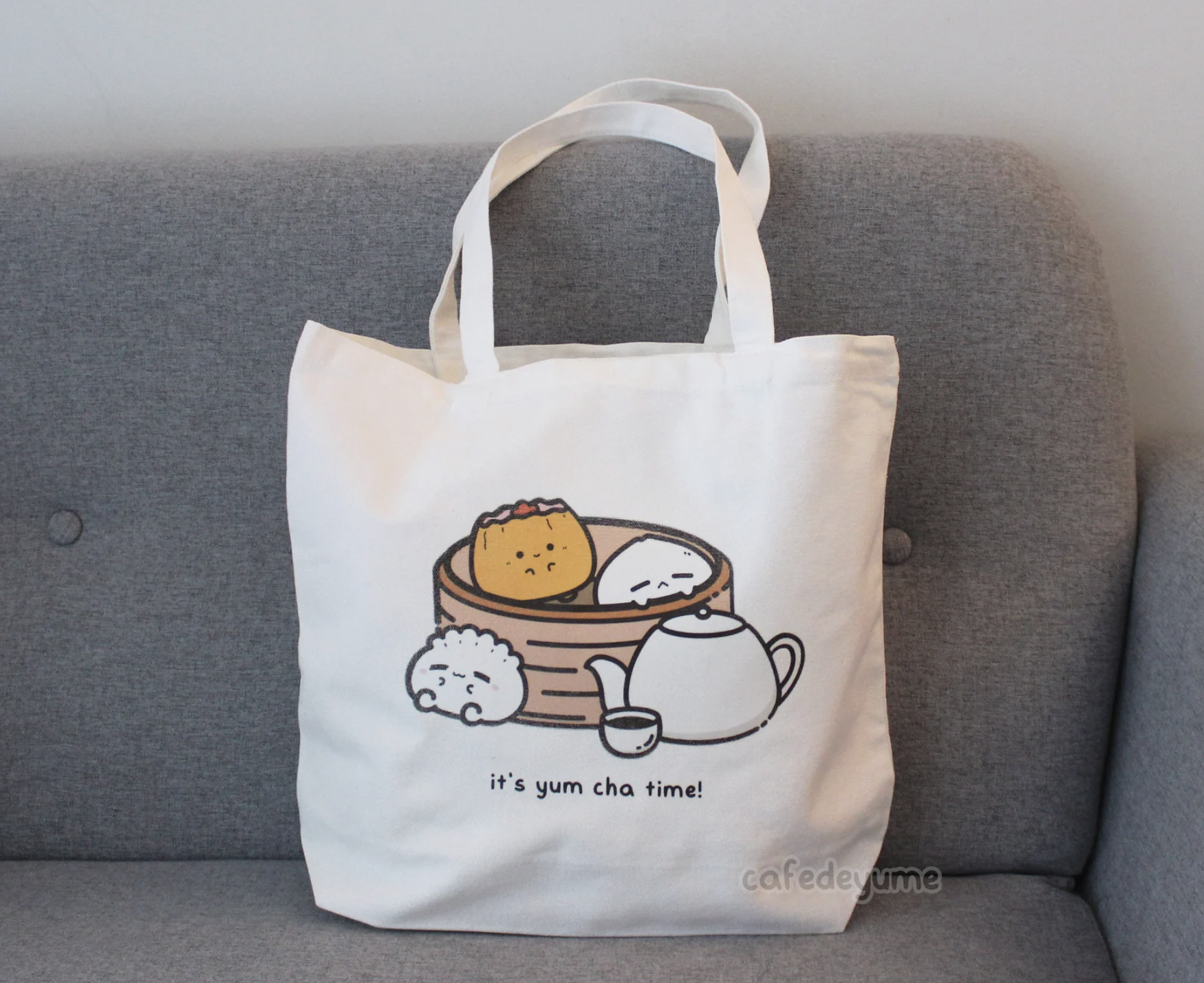 Tote bag with cartoon dim sum characters on a couch.
