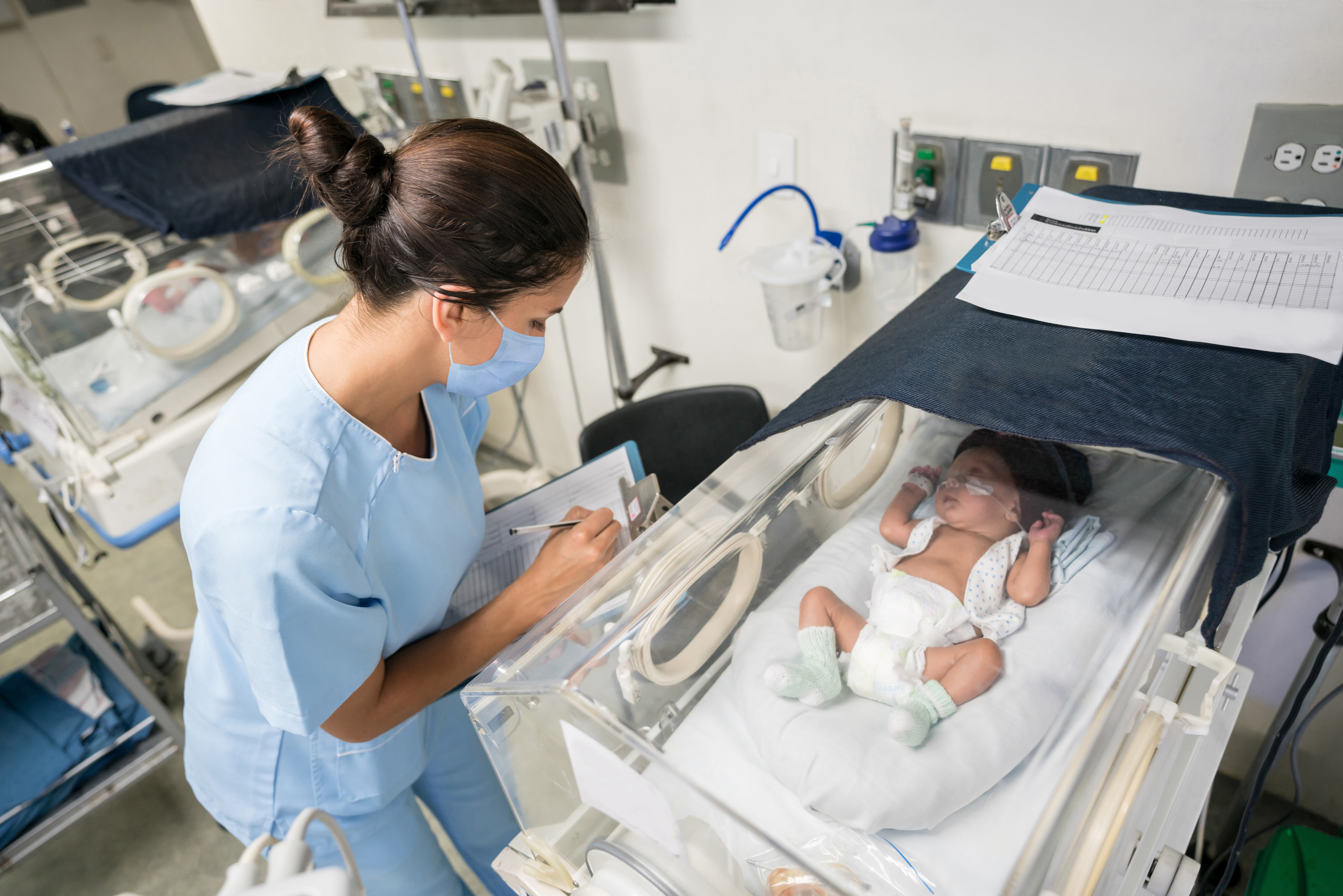 Nurse checking on a baby in an incubator