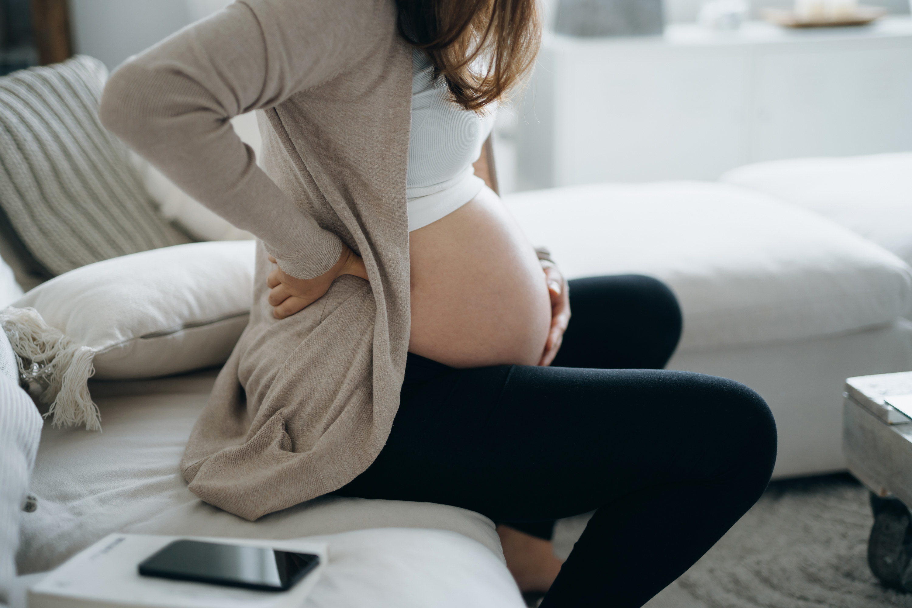 Pregnant woman holding her lower back in pain