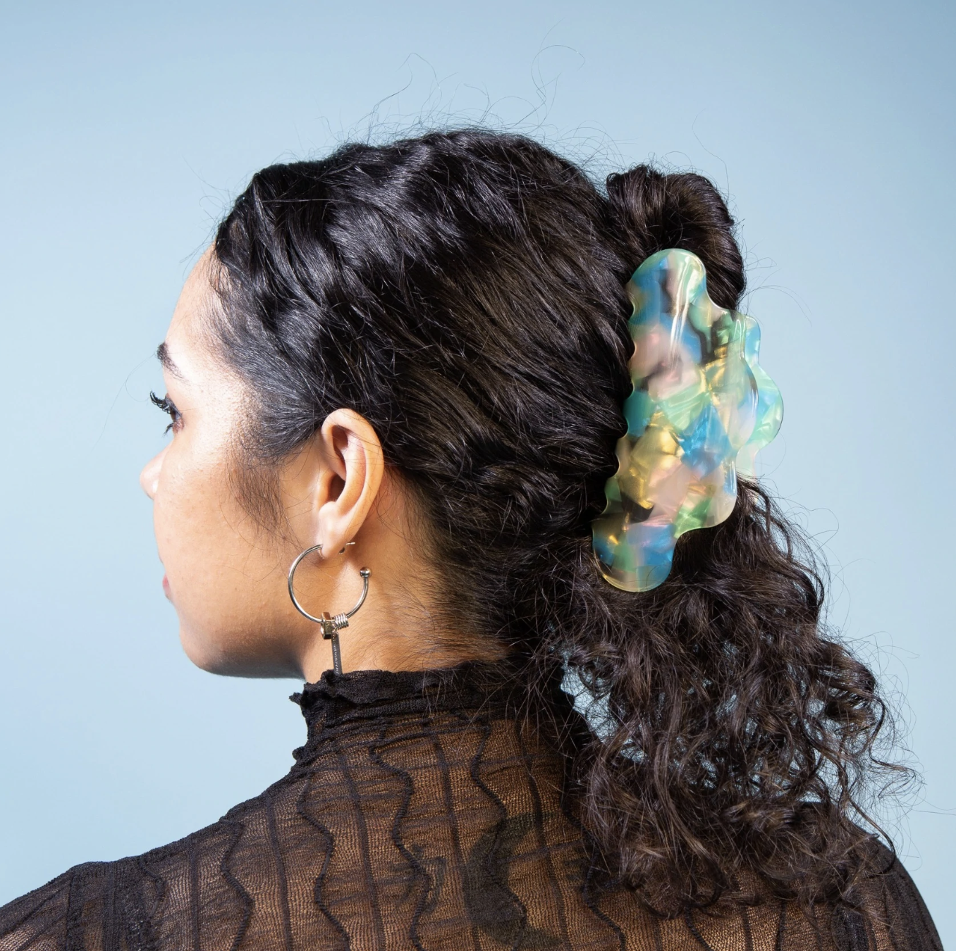 Cloud shaped hairclip holding up a model&#x27;s curly hair.